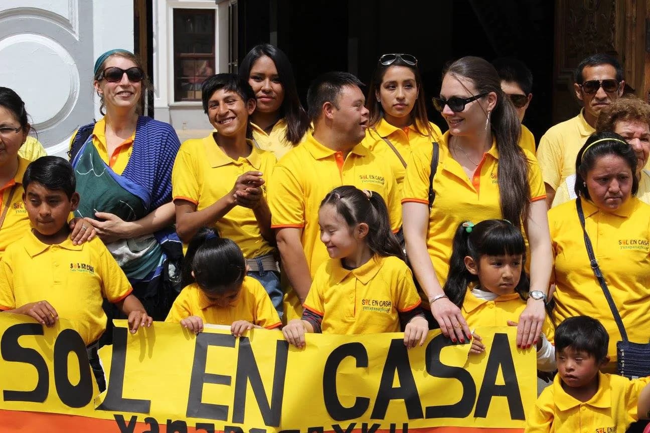Miembros de Sol en Casa Yanapasayku reunidos con una pancarta de la fundación